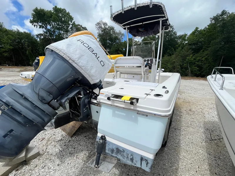 Slide: The Image of 2016 Robalo 206 Cayman boat with outboard motor, parked on gravel, surrounded by trees. - 9