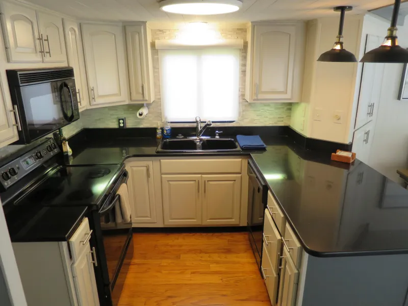 Slide: The Image of Modern kitchen in a 1998 Monticello River Yacht Houseboat with black countertops and white cabinets. - 13