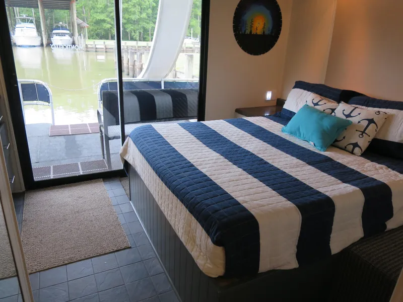 Slide: The Image of 1998 Monticello River Yacht Houseboat bedroom with striped bedding and waterfront view. - 18