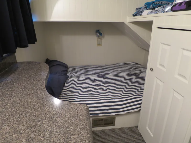 Slide: The Image of 1998 Monticello River Yacht Houseboat cozy bedroom with striped bedding and granite countertop. - 22