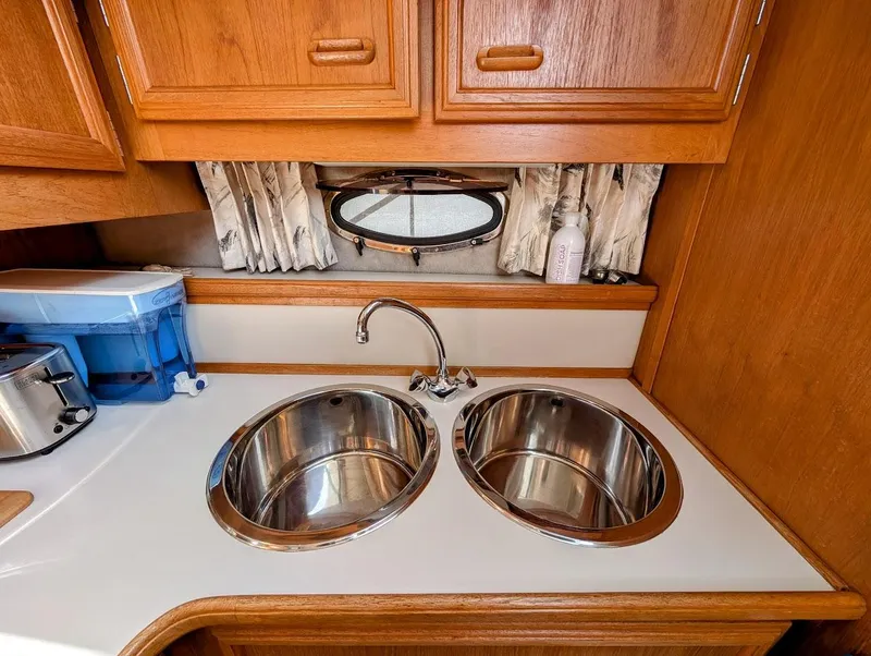 Slide: The Image of 1991 Carver 430 Cockpit Motor Yacht kitchen with dual sinks and wooden cabinetry. - 17