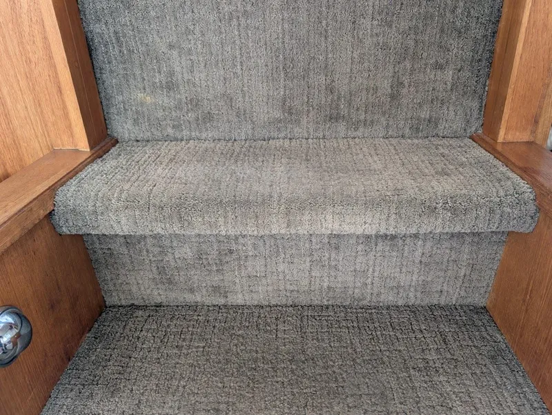 Slide: The Image of Carpeted stairs inside 1991 Carver 430 Cockpit Motor Yacht with wooden trim. - 25