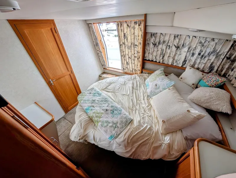 Slide: The Image of Cozy bedroom in 1991 Carver 430 Cockpit Motor Yacht with plush bedding and wooden accents. - 26