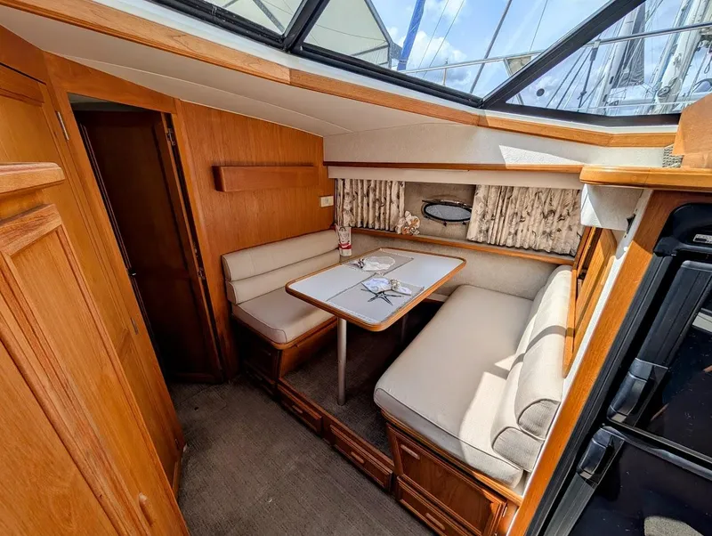 Slide: The Image of 1991 Carver 430 Cockpit Motor Yacht interior with cozy dining area and wooden finishes. - 18