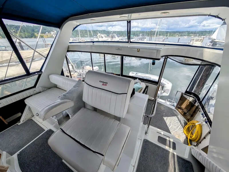 Slide: The Image of Interior of 1991 Carver 430 Cockpit Motor Yacht with white seating and marina view. - 36