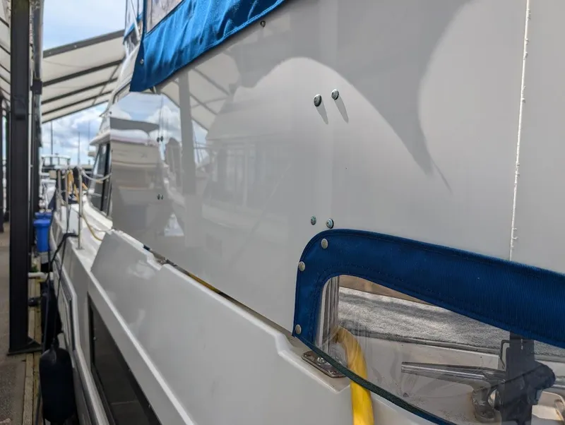 Slide: The Image of 1991 Carver 430 Cockpit Motor Yacht docked, featuring blue canvas and sleek white exterior. - 4