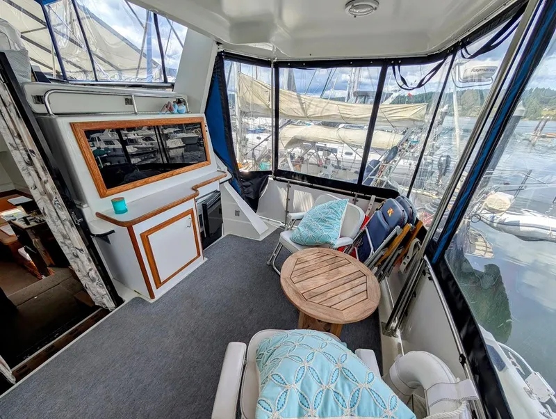 Slide: The Image of 1991 Carver 430 Cockpit Motor Yacht interior with seating, table, and marina view. - 6