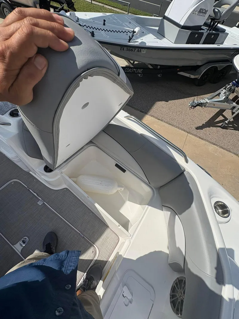 Slide: The Image of 2021 NauticStar 203 SC boat interior with open storage compartment and gray seating. - 11