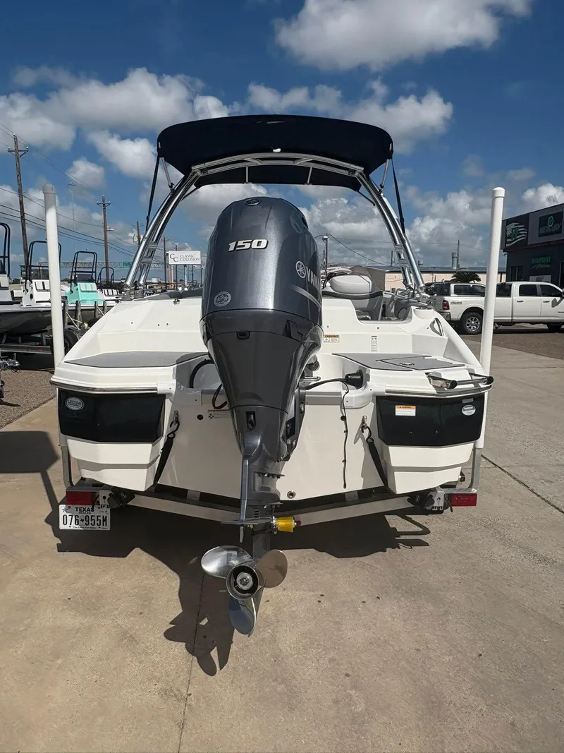 Slide: The Image of 2021 NauticStar 203 SC boat with Yamaha 150 engine, parked outdoors under blue sky. - 13