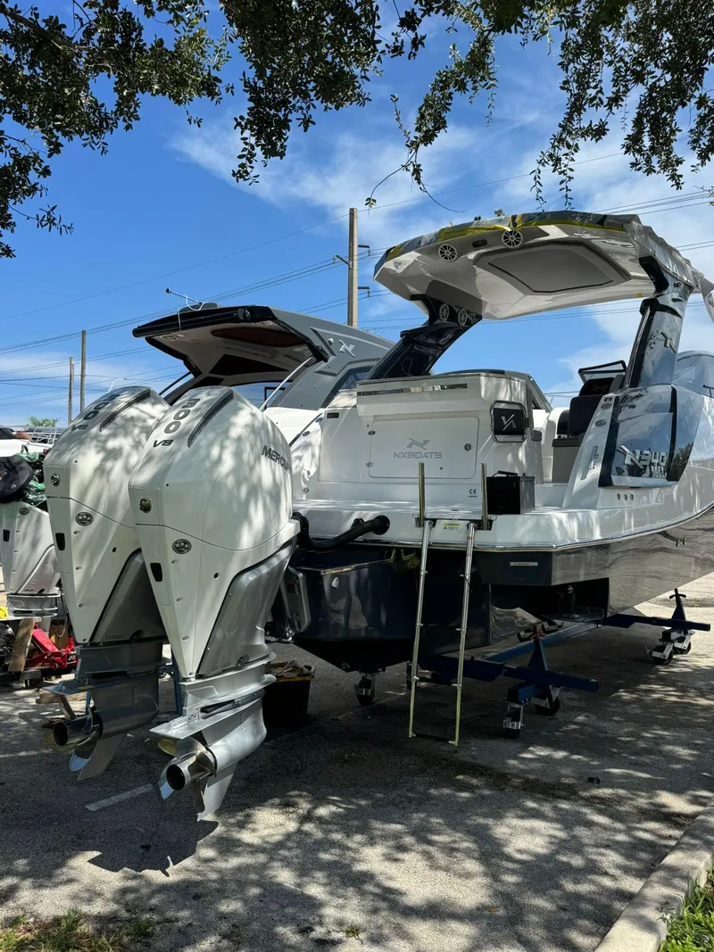 Slide: The Image of 2025 NX Boats NX340 with dual outboard motors, parked under a tree. - 4