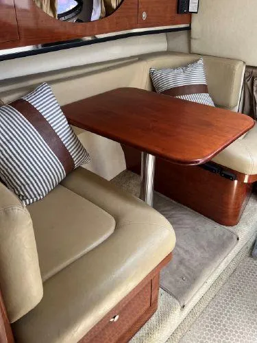 Slide: The Image of 2007 Sea Ray 290 Amberjack interior with cushioned seating and wooden table. - 10