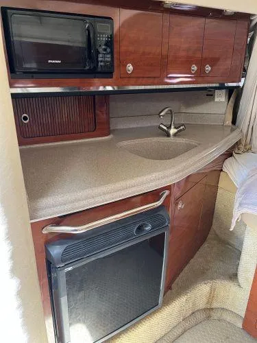 Slide: The Image of 2007 Sea Ray 290 Amberjack cabin kitchen with microwave, sink, and fridge. - 11