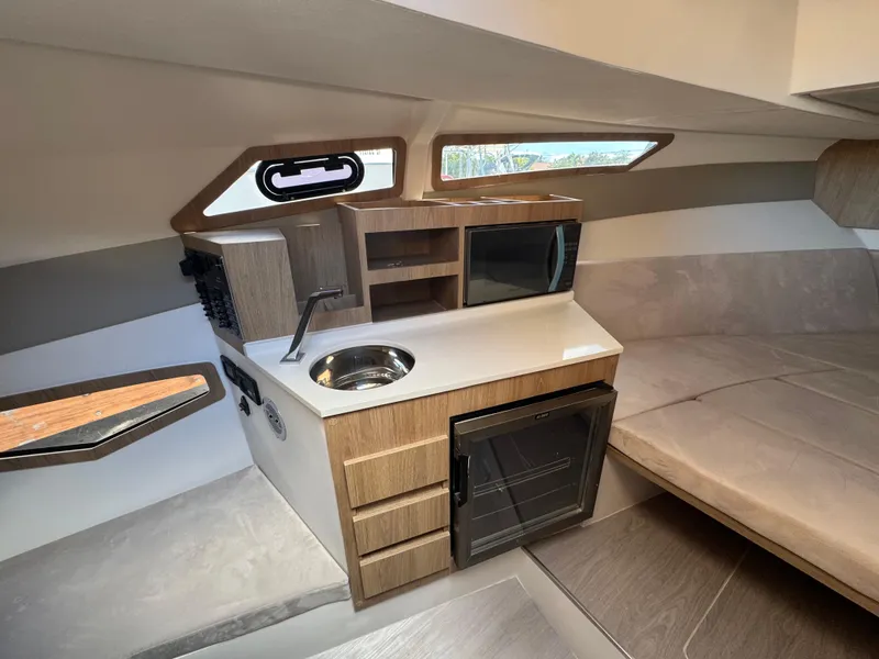 Slide: The Image of Interior of 2025 NX Boats NX340, featuring kitchenette with sink, microwave, and mini-fridge. - 7