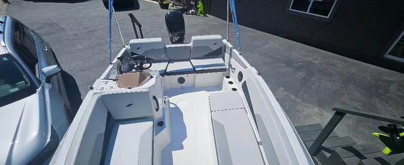 Slide: The Image of 2026 Starcraft SV 16 OB boat interior with seating, parked beside a silver car. - 7