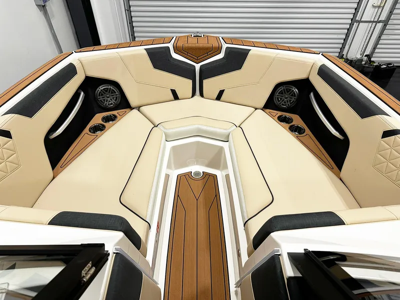 Slide: The Image of 2026 Nautique GS24 boat interior with beige and black seating, cup holders, and speakers. - 6