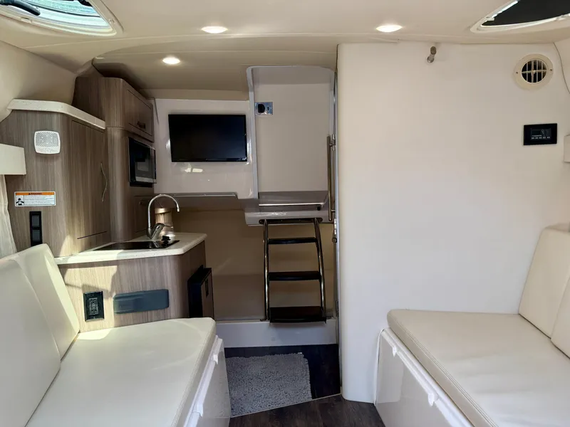 Slide: The Image of 2019 Regal 28 Express cabin interior with kitchenette, seating, and TV. - 25