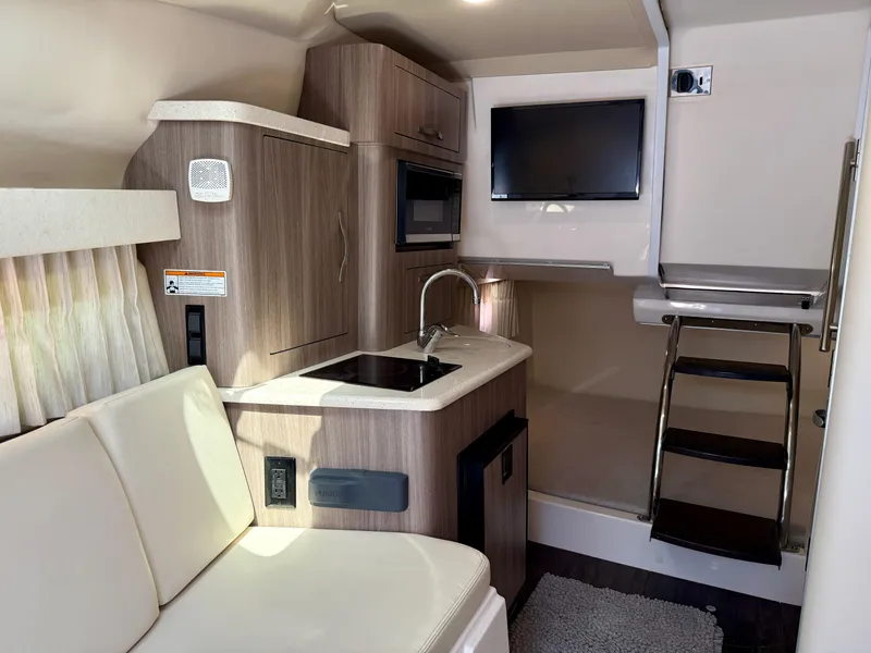 Slide: The Image of 2019 Regal 28 Express boat interior with kitchenette, TV, and seating area. - 26