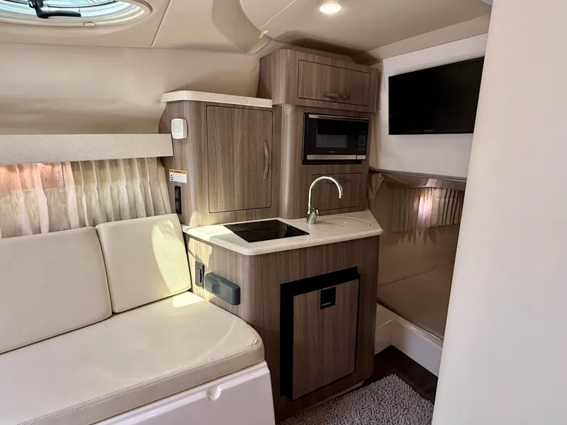 Slide: The Image of 2019 Regal 28 Express boat interior with kitchenette, featuring sink, microwave, and seating area. - 27