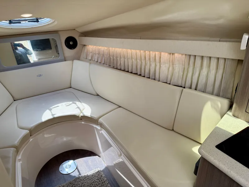 Slide: The Image of 2019 Regal 28 Express cabin interior with cream seating and natural light. - 30