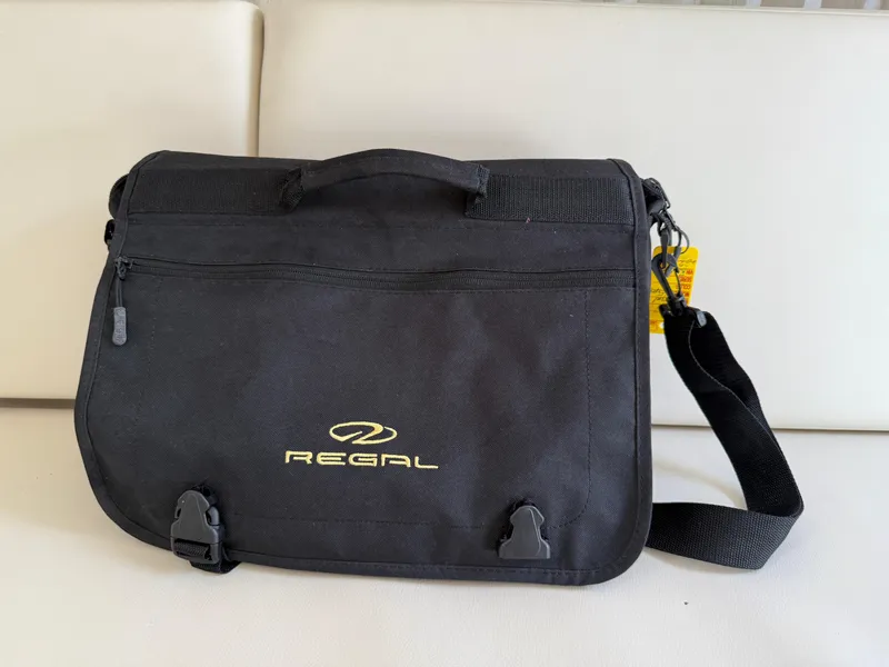 Slide: The Image of Black Regal branded messenger bag on a white surface, featuring a shoulder strap. - 45