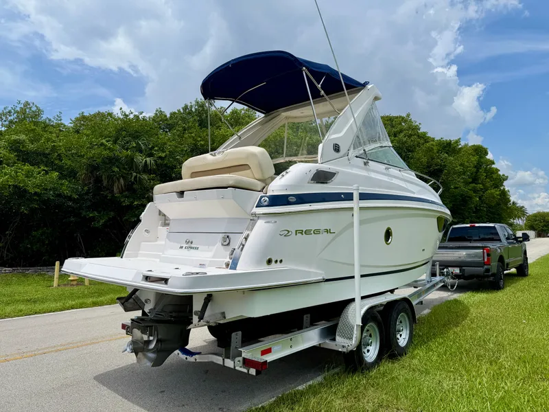 Slide: The Image of 2019 Regal 28 Express boat on trailer, parked on roadside with lush greenery. - 5