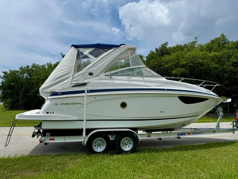 Slide: The Image of 2019 Regal 28 Express boat on trailer, parked on grass, under cloudy sky. - 9