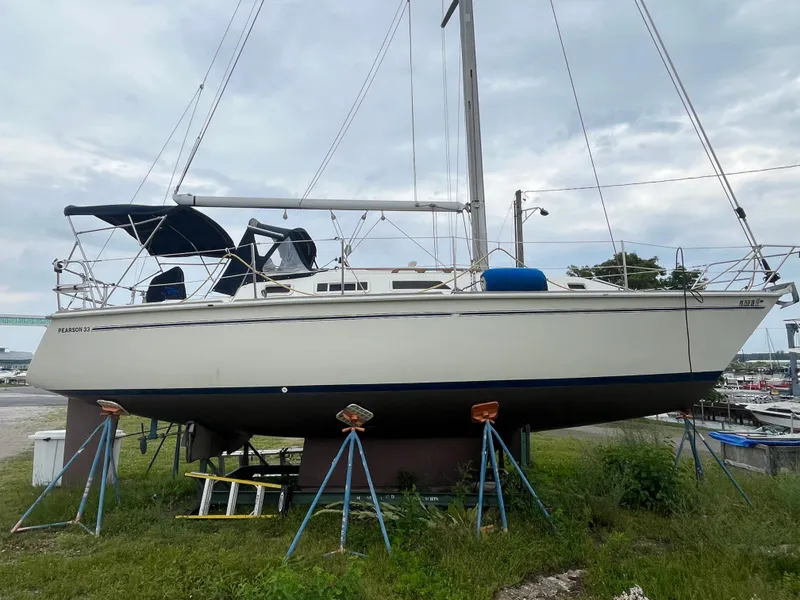 The Image of 1986 Pearson 33-2 sailboat on stands, ready for maintenance at a marina. - 1