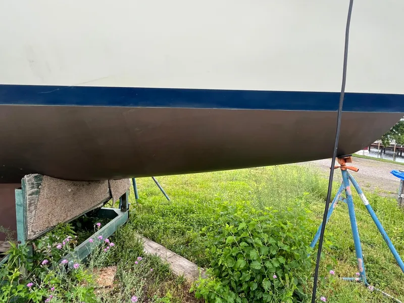 Slide: The Image of Pearson 33-2 sailboat hull, 1986 model, on stands with greenery around. - 10