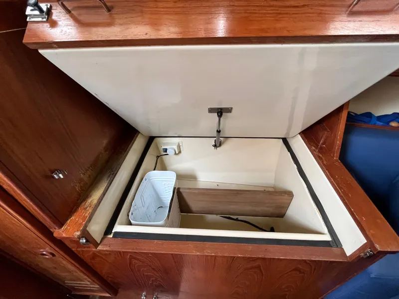 Slide: The Image of Open storage compartment in 1986 Pearson 33-2 sailboat with wooden trim and white interior. - 16