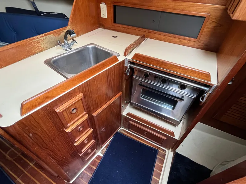 Slide: The Image of 1986 Pearson 33-2 yacht galley with sink, stove, and wooden cabinetry. - 24