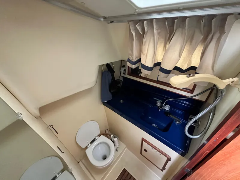 Slide: The Image of 1986 Pearson 33-2 yacht bathroom with toilet, blue sink, and showerhead. - 27
