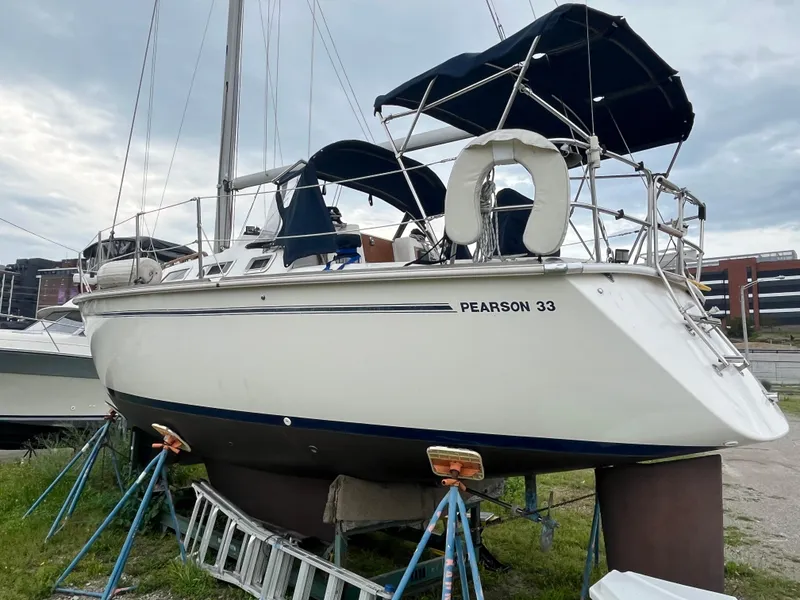 Slide: The Image of 1986 Pearson 33-2 sailboat on stands, with blue canvas covers, docked outdoors. - 4