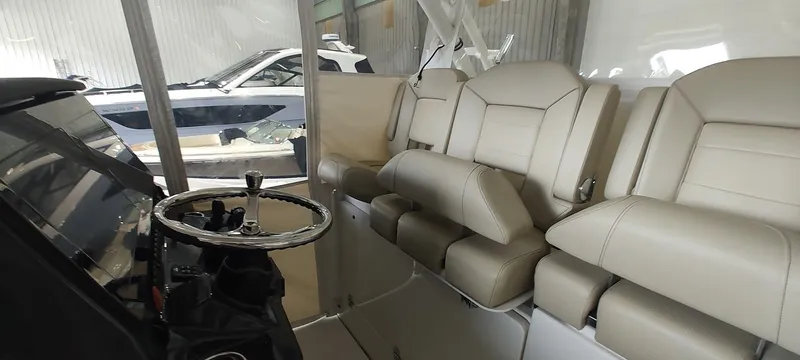 Slide: The Image of 2020 Pursuit S 368 Sport boat interior with beige seating and steering wheel in a showroom. - 24