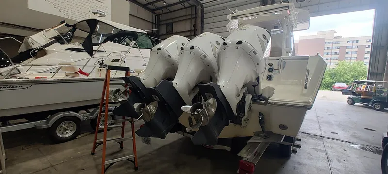 Slide: The Image of 2020 Pursuit S 368 Sport boat with triple outboard engines in a garage setting. - 32