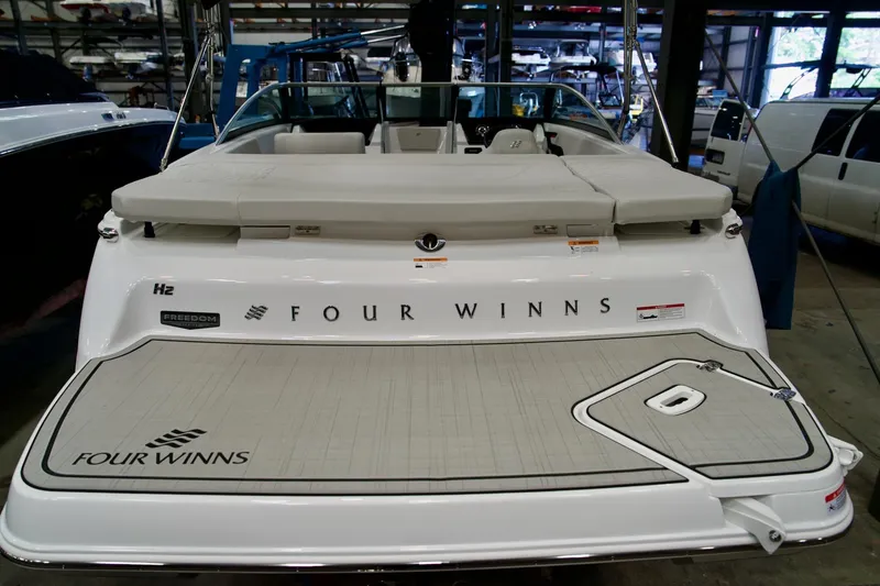 Slide: The Image of 2026 Four Winns H2 boat in a showroom, rear view with branding visible. - 7