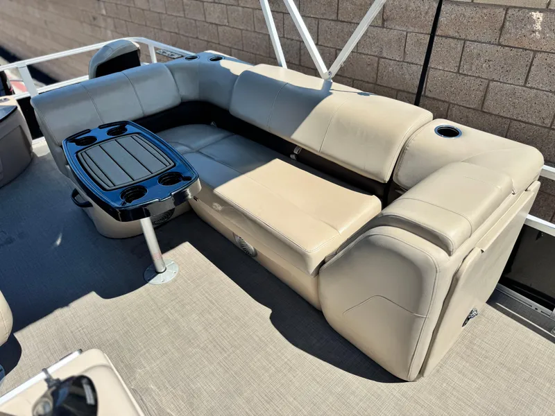 Slide: The Image of 2019 Sun Tracker Fishin' Barge 20 DLX interior with beige seating and a central table. - 13