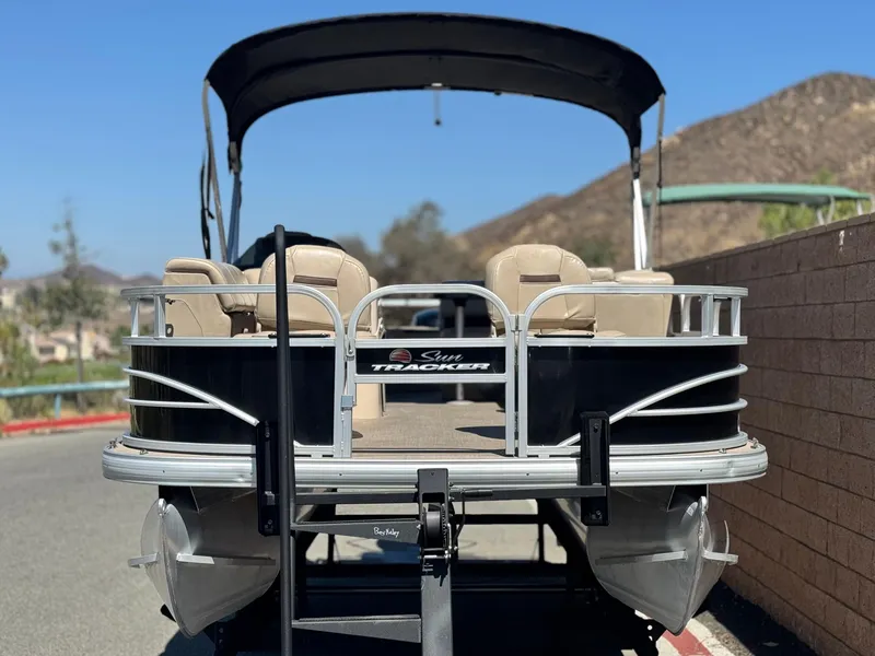 Slide: The Image of 2019 Sun Tracker Fishin' Barge 20 DLX pontoon boat on trailer, scenic background. - 2