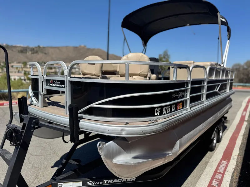 Slide: The Image of 2019 Sun Tracker Fishin' Barge 20 DLX pontoon boat on trailer, parked outdoors. - 3