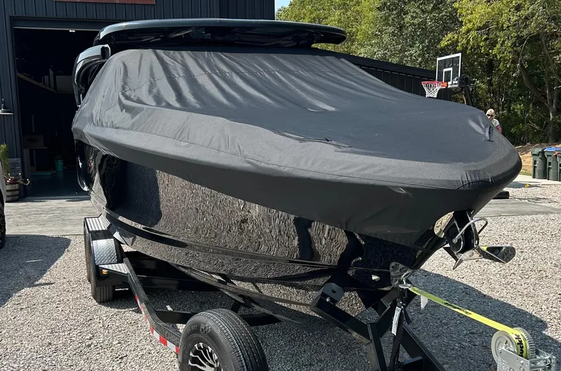 Slide: The Image of 2022 Chaparral 307 SSX boat covered on trailer, parked outdoors. - 13