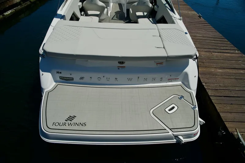 Slide: The Image of 2026 Four Winns H4 boat docked, showcasing spacious deck and seating. - 9