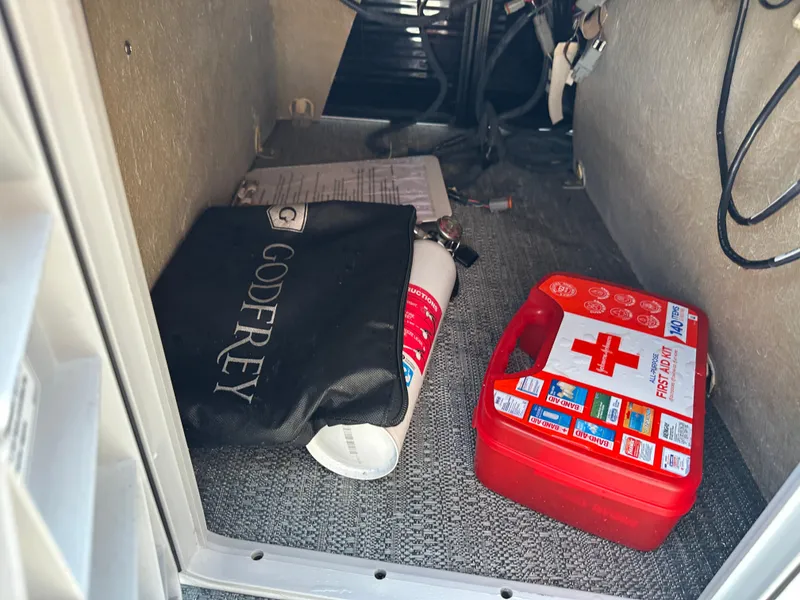 Slide: The Image of Storage compartment in a 2022 Godfrey SWEETWATER 2286 SFL with first aid kit and fire extinguisher. - 11