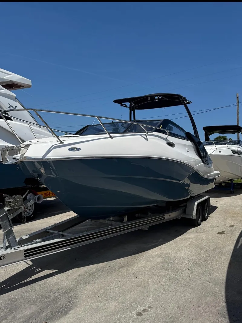 The Image of 2025 NX Boats NX270 on trailer, sleek design, parked outdoors under clear blue sky. - 1