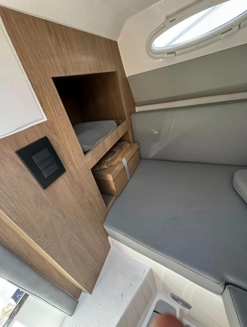 Slide: The Image of Interior of 2025 NX Boats NX270, featuring cozy seating and wooden storage. - 11