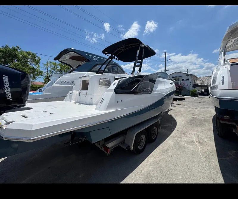 Slide: The Image of 2025 NX Boats NX270 on trailer under clear blue sky. - 2
