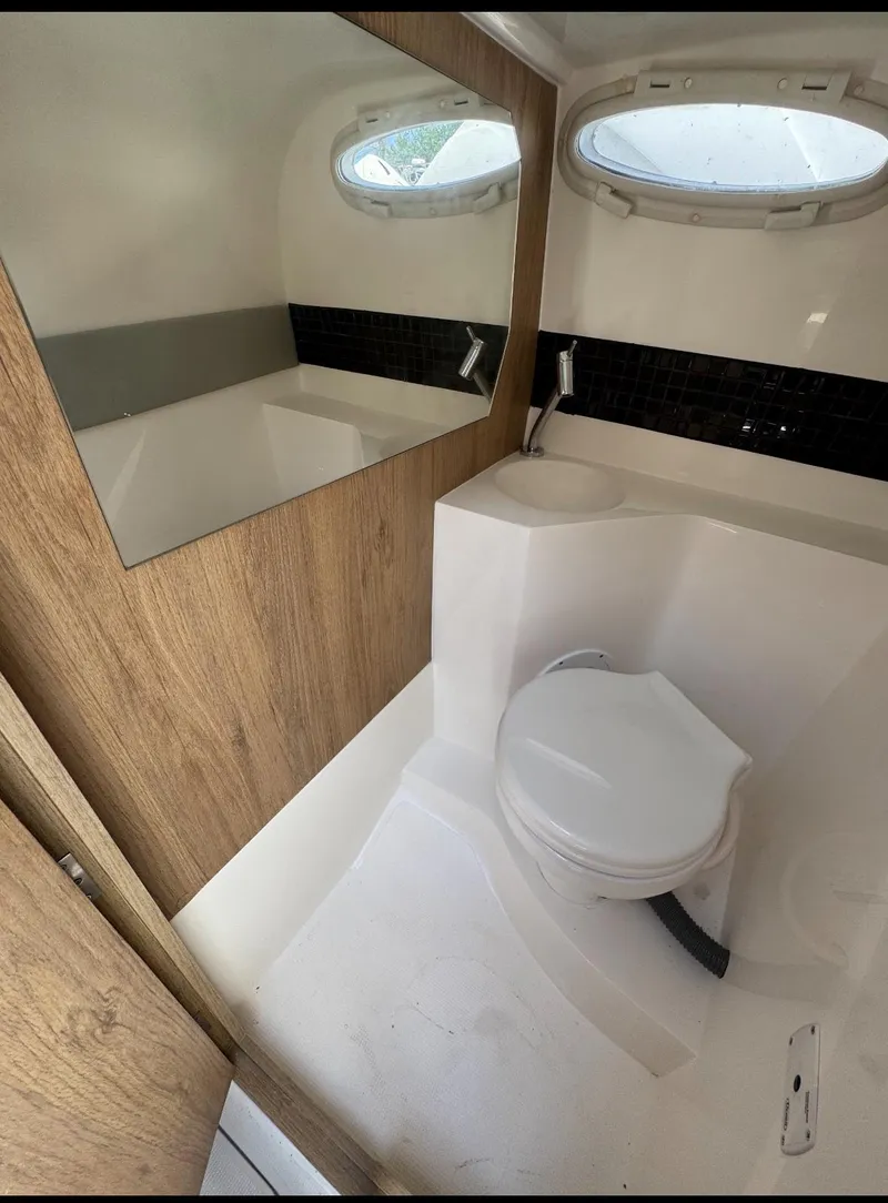 Slide: The Image of Bathroom interior of 2025 NX Boats NX270, featuring modern fixtures and wood accents. - 6
