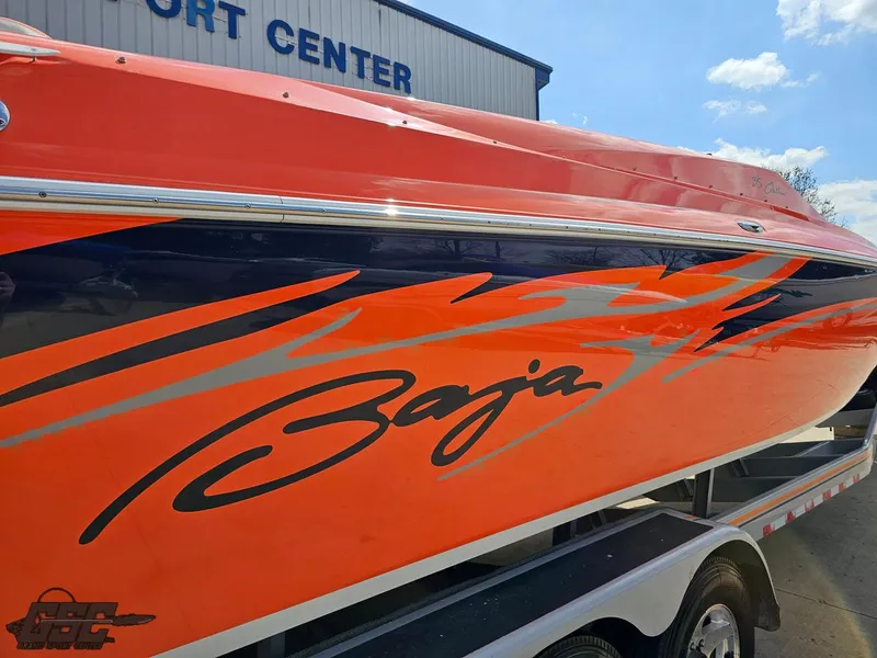 Slide: The Image of 2007 Baja 35 Outlaw boat with vibrant orange and blue graphics, parked at a sport center. - 14