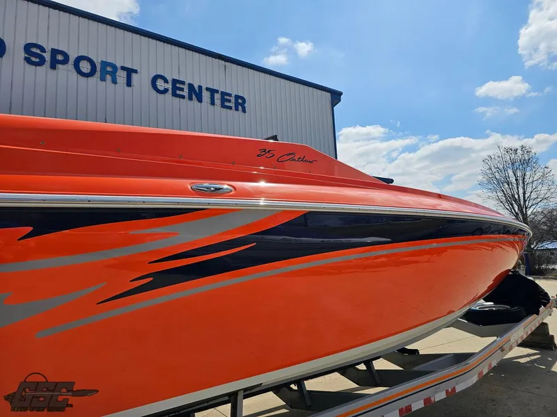 Slide: The Image of 2007 Baja 35 Outlaw boat with vibrant orange and blue design at a sport center. - 15
