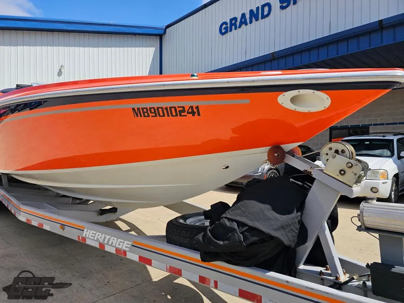 Slide: The Image of 2007 Baja 35 Outlaw boat on trailer, vibrant orange hull, parked outside a building. - 16