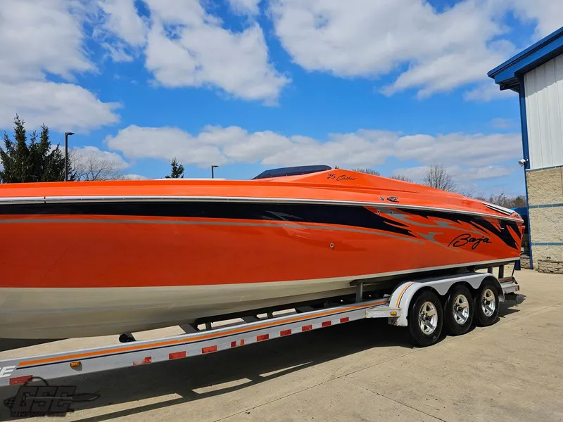 Slide: The Image of 2007 Baja 35 Outlaw speedboat in vibrant orange on a trailer, under a blue sky. - 20