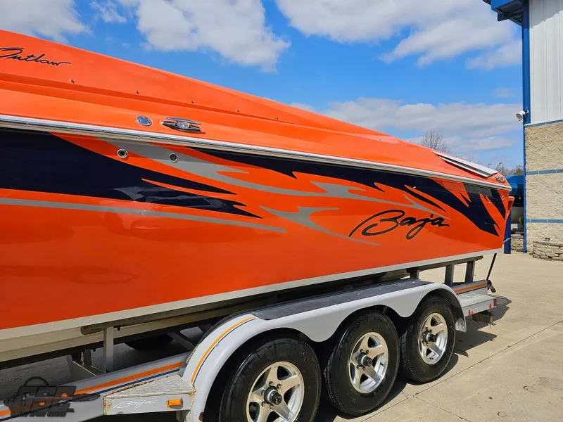 Slide: The Image of 2007 Baja 35 Outlaw boat with vibrant orange and blue design on a trailer. - 21